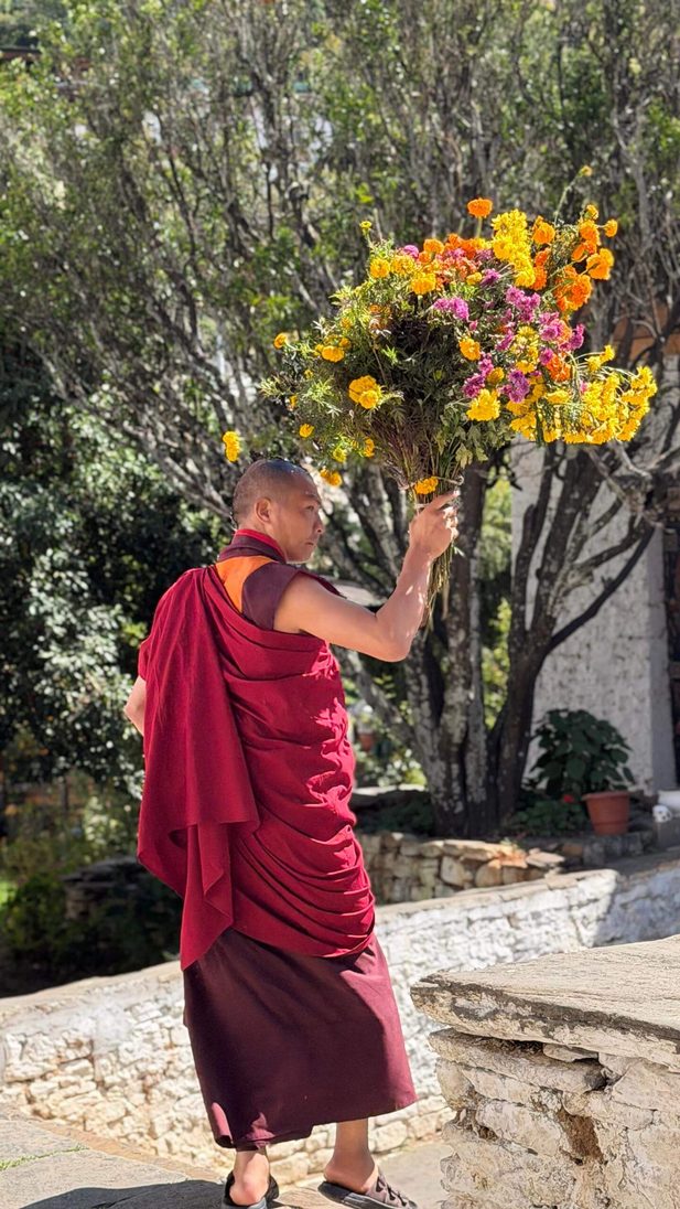 Monk holds colorful flower bouquet.