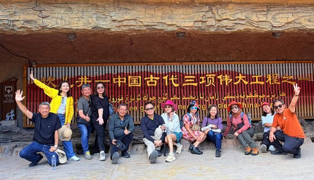 李桑 ‧ 乘坐“锦绣天府号”列车 ‧ 悠游南北疆10488公里文 group poses in front of sign