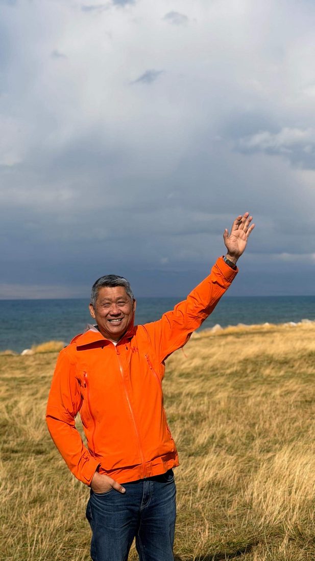 Man waving by the ocean.