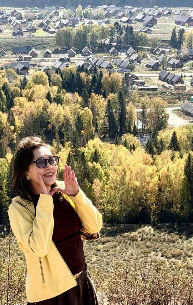 李桑 ‧ 乘坐“锦绣天府号”列车 ‧ 悠游南北疆10488公里文 Woman enjoys autumn village vista.