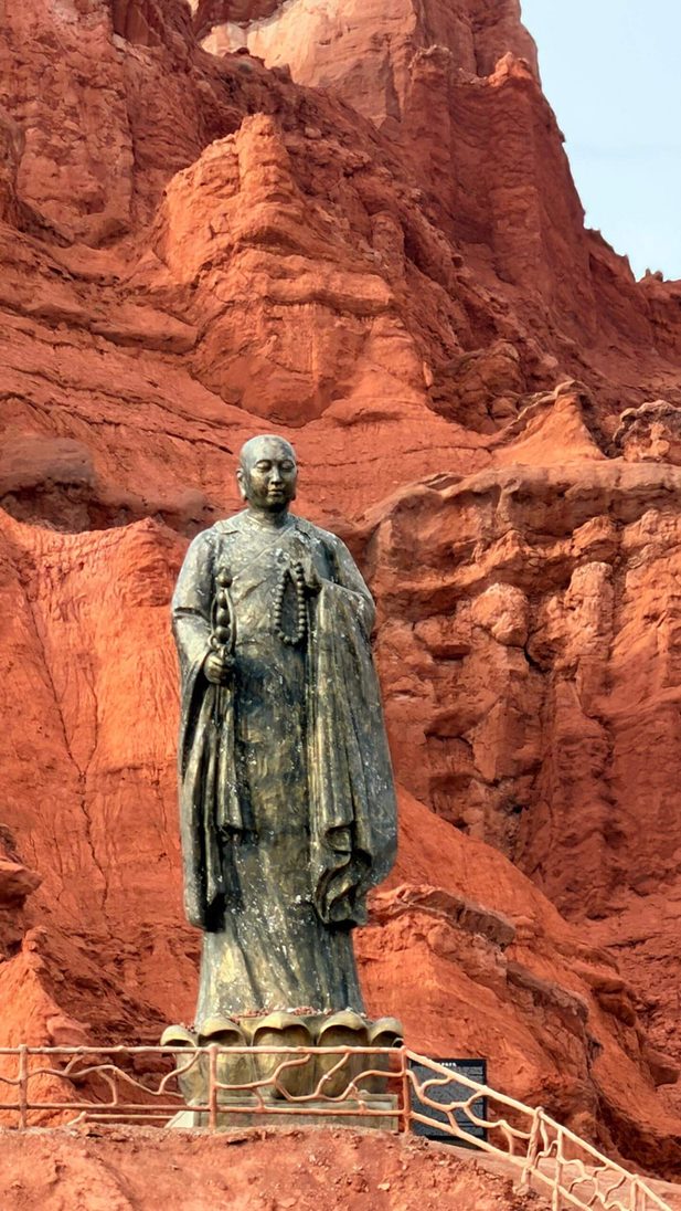 李桑 ‧ 乘坐“锦绣天府号”列车 ‧ 悠游南北疆10488公里文 Statue in front of red rock.